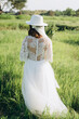 © Denys - stylish woman in fedora hat  white dress walking in the field with trees
