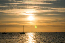 Beautiful Yellow Sunset With The Ocean And Sailing Boats In The Forground