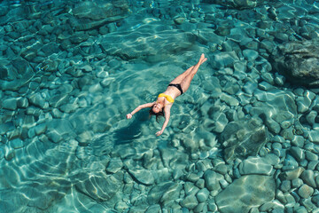 Wall Mural - A woman swims in blue sea water in the bay. Nature and relaxation, top view