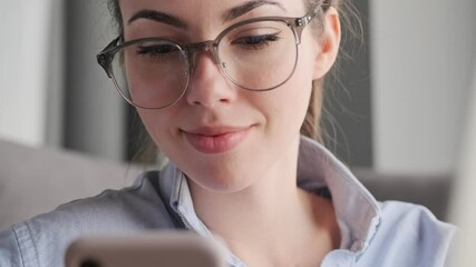 Wall Mural - Close up view of Happy attractive brunette woman in eyeglasses using smartphone and laptop computer at home