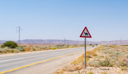 Camel crossing road sign on a way through the desert