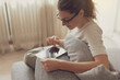© stokkete - Woman relaxing on the sofa and connecting with her touch screen tablet