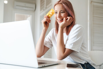 Sticker - Photo of cheerful woman working with laptop and holding credit card