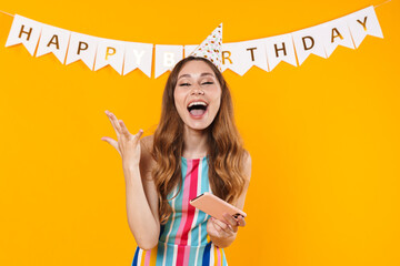 Canvas Print - Image of excited woman in party cone playing online game on cellphone