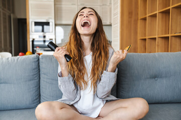 Canvas Print - Cheerful young woman relaxing on a couch at home