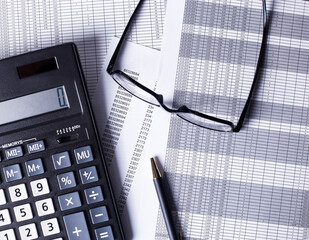 On a light table are documents, a pen, a calculator, a glasses. Business concept