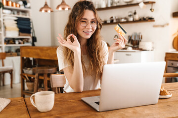 Poster - Lovely cheerful young girl sitting at the kitchen table