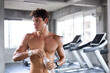 © winnievinzence - Young Caucasian muscular athletic man in shirtless holding water in gym fitness after workout exercise. people lifestyle for better health with copy space