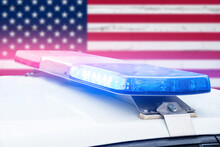 Police Car With Red And Blue Lights On A United States Of America Flag Background.