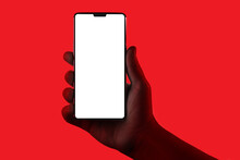 Hand Holding Phone. Silhouette Of Male Hand Holding Smartphone Isolated On Red Background. Bezel-less Screen Is Cut With Clipping Path.