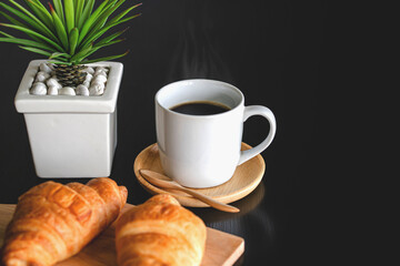 Two fresh croissants and cup of coffee on dark stone table