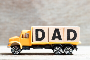 Truck hold letter block in word dad on wood background