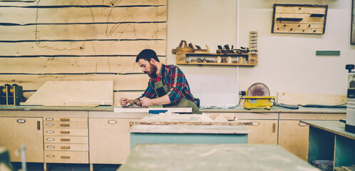 Wall Mural - bearded handsome cabinet maker at tabletop polishing wooden during working process at his workstatio