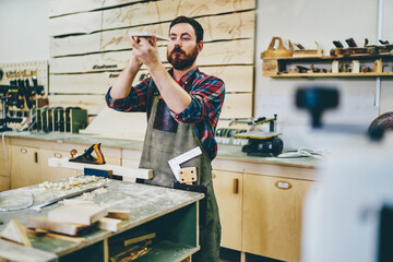 Wall Mural - bearded carpenter enjoying hobby working process at his workstation of manufacturing, side view of s