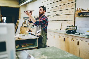 Wall Mural - serious bearded man spending time on hobby making diy furniture using timber and equipment in garage