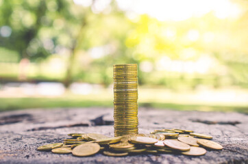 row of coin stack on wood table with blur nature park background. money saving concept for financial banking and accounting.