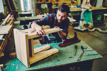 Wall Mural - caucasian craftsman making measurements for decorative chair during woodworking hobby in manufacturi