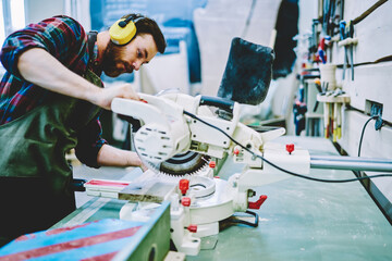 Wall Mural - caucasian foreman using electronic circular during diy handmade hobby for making wooden plank in own