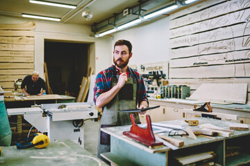 Wall Mural - pensive bearded male owner of manufacture workshop standing with notebook thinking about planning bu
