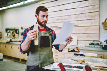 Wall Mural - young bearded guy read instruction for making handmade details on courses learning woodworking carpe