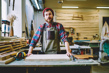 Wall Mural - half length portrait of prosperous male owner of craft store standing at working place with equipmen