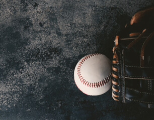 Sticker - Baseball glove and ball for sport game laying on dark grunge texture background.