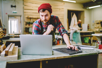 Wall Mural - serious bearded male master checking information from website while creating sketch and plannings fo