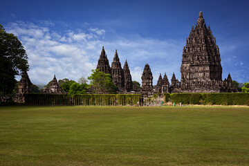 Wall Mural - Prambanan Hindu Temple view in Yogyakarta, Java Island, Indonesia, its most beautiful Hindu temple in Indonesia. View with blue sky background and green grass garden foreground