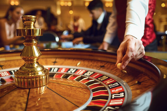 hand of a croupier with a ball on a roulette wheel during a game in a casino.