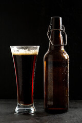 Dark crafted beer in glass and bottle on black background