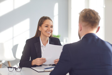 Successful interview. Positive girl employer listens to a job seeker sitting at a table in the office.