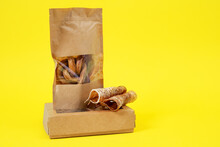 Craft Box And Package With Transparent Top With Tasty Dried Snacks For Pets Inside On Yellow Background, Close Up, Copy Space For Advertising Text. Pet Care. Pet Supplies.
