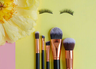 premium makeup brushes on a colored pink and yellow background, creative cosmetics flat lay