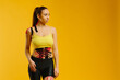 © dsheremeta - Young caucasian girl with kinesiology tape on her belly and leg, on yellow background. Sport and rehabilitation, kinesiotherapy treatment.