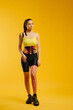 © dsheremeta - Young caucasian girl with kinesiology tape on her belly and leg, on yellow background. Sport and rehabilitation, kinesiotherapy treatment.