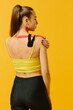 © dsheremeta - Young caucasian girl with kinesiology tape on her belly and leg, on yellow background. Sport and rehabilitation, kinesiotherapy treatment.