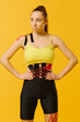 © dsheremeta - Young caucasian girl with kinesiology tape on her belly and leg, on yellow background. Sport and rehabilitation, kinesiotherapy treatment.