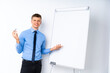 © luismolinero - Young businessman giving a presentation on white board giving a presentation on white board