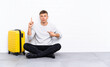 © luismolinero - Young handsome man sitting on the floor with a suitcase with surprise facial expression
