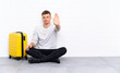 © luismolinero - Young handsome man sitting on the floor with a suitcase making stop gesture with her hand