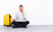 © luismolinero - Young handsome man sitting on the floor with a suitcase thinking an idea