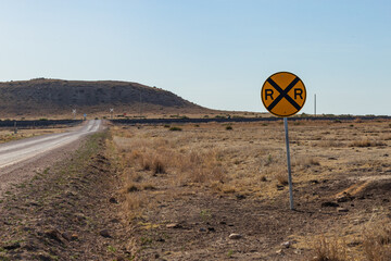 Wall Mural - Railroad crossing sign on lonely country road in the desert or prairie