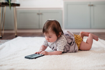 Child on the floor playing with a cell phone