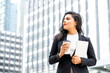 © Atstock Productions - Portrait of beautiful young confident Hispanic businesswoman taking a coffee break holding tablet in urban city background