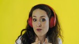 Fototapeta Łazienka - Woman listening to music with red headphones in Studio with yellow Background.