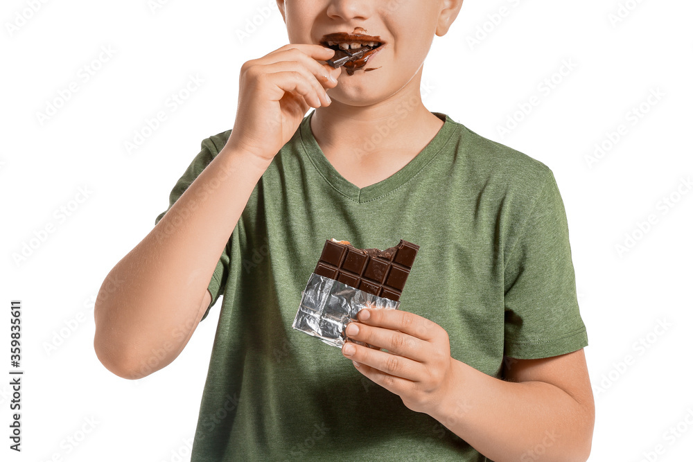 Cute little boy eating chocolate on white background