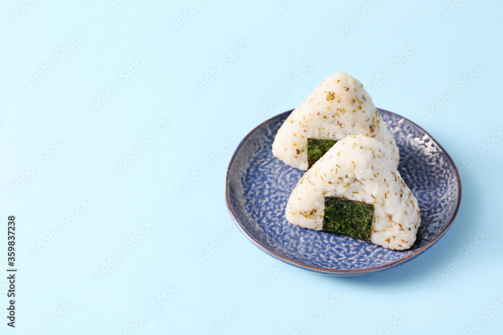 Plate with traditional Japanese onigiri on color background