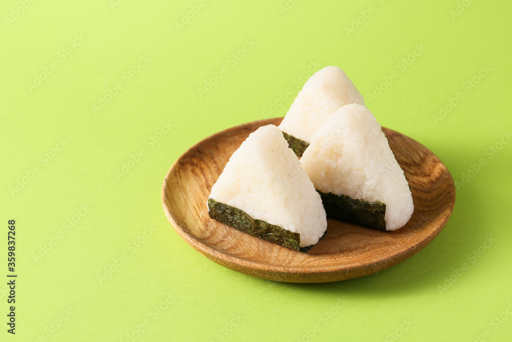 Plate with traditional Japanese onigiri on color background