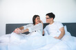 © chokniti - happy young couple wake up in bed and smiling raise arms in the morning, asian lovers on white bed