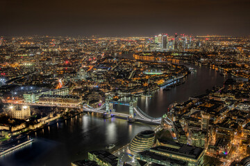 Wall Mural - Aerial photograph of  London city and Tower Bridge and the River Thames at night showing city lights leading to Canary Wharf, London England. 